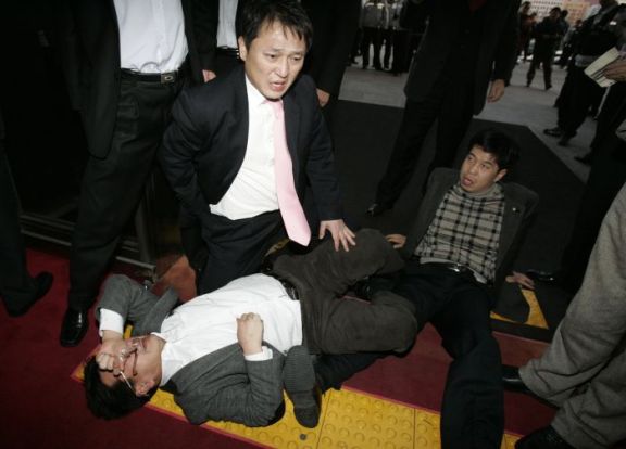 Lawmakers of the main opposition Democratic Party react as they fall down during scuffles with parliament security guards in Seoul